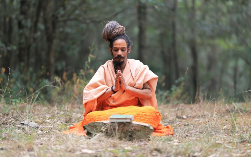 man meditating on wellness retreat in Indian forest