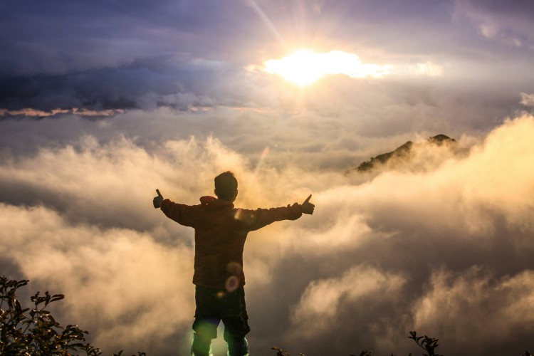 man overlooking cloudy view atop a mountain
