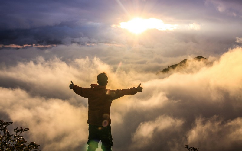 man overlooking cloudy view atop a mountain