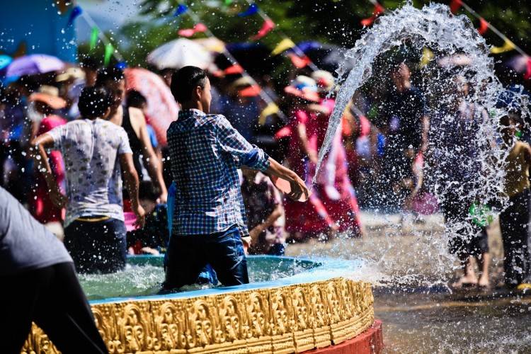 Boy splashing water in fountain during water-Sprinkling Festival in Yunnan, China