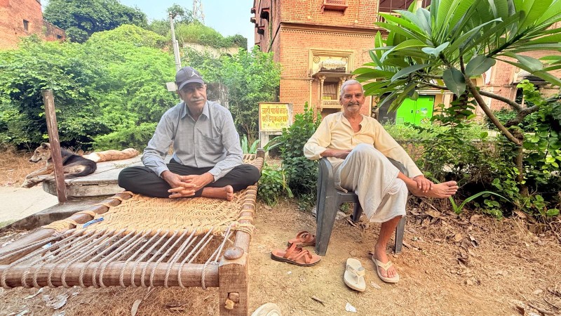 Holipur village elderly men sitting outside on a wooden bed