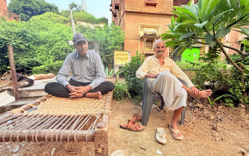Holipur village elderly men sitting outside on a wooden bed